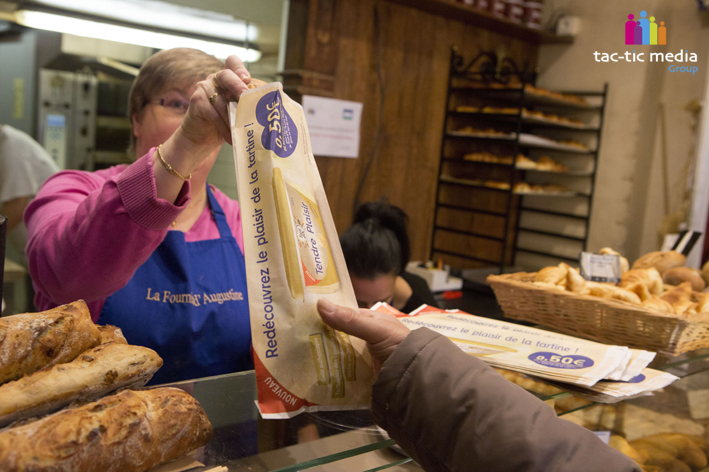 boulangère qui donne une baguette dans un sac à pain Fruit d'Or